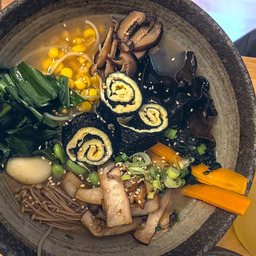 A closeup of a bowl with all ingredients aesthetically arranged on top of noodles and broth.