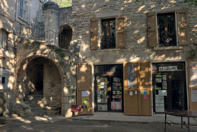 A small book shop in an old stone building with a beautiful winding outside staircase. It is a late summer afternoon and the trees in the background create a beautiful warm pattern on the walls.