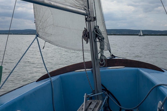 View from the cockpit of a small sailingboat. The water is fairly calm, there is another boat further away.