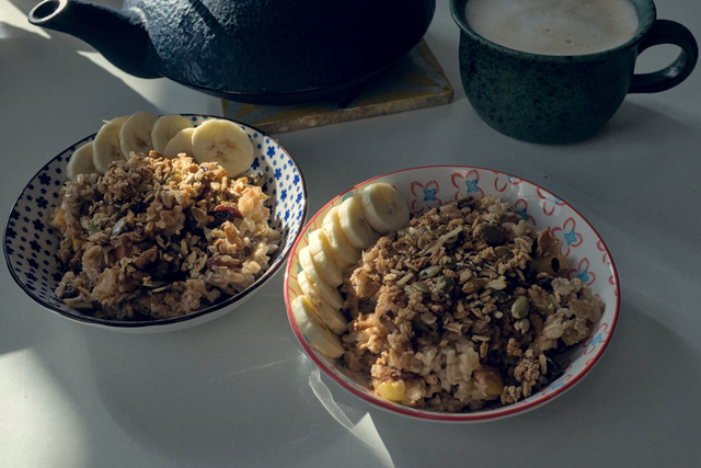 Two bowls of porridge on a table with a black teapot in the background.
