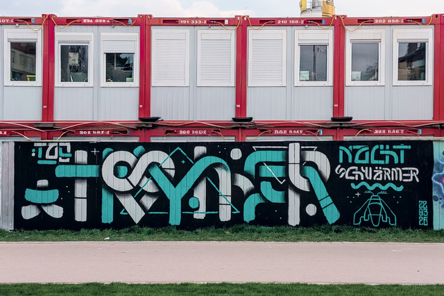 A large painted mural reading the letters TAG TROYMER (misspelled daydreamer) and NACHTSCHWÄRMER (night swarmers).