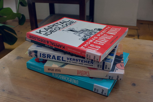 A stack of 5 books on a small wodden table. The books are Kapital & Ideolog Thomas Piketty as a graphic novel, Death by Neil Gaiman, Israel verstehen in 60 Tagen oder weniger by Sarah Glidden, Diebin bei Lucie Bryon and Unerschroken by Pénélope Bagieu.