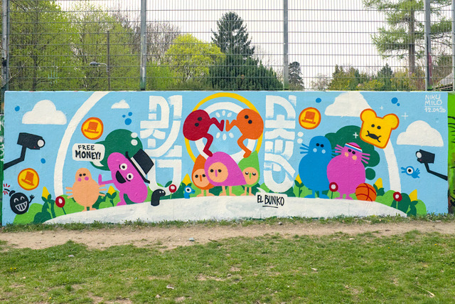 A painted wall with lots of colorful characters from the game Piku Niku. In the center there are Piku and Niku high fiveing with their feet.