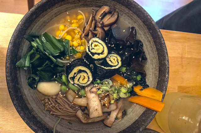 A closeup of a bowl with all ingredients aesthetically arranged on top of noodles and broth.